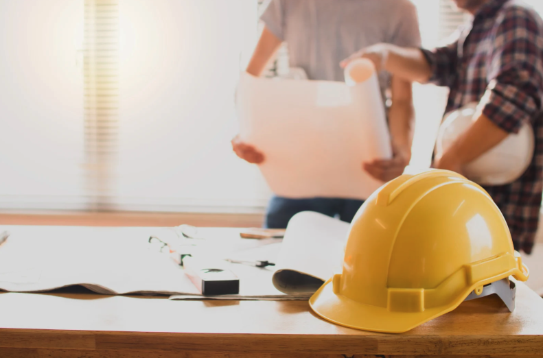 Two industrial concrete contractors discussing blueprints and safety concerns.